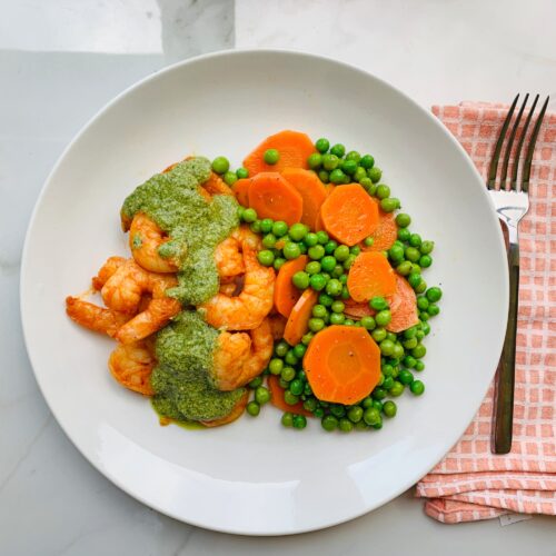 Pesto shrimp served with carrots and peas